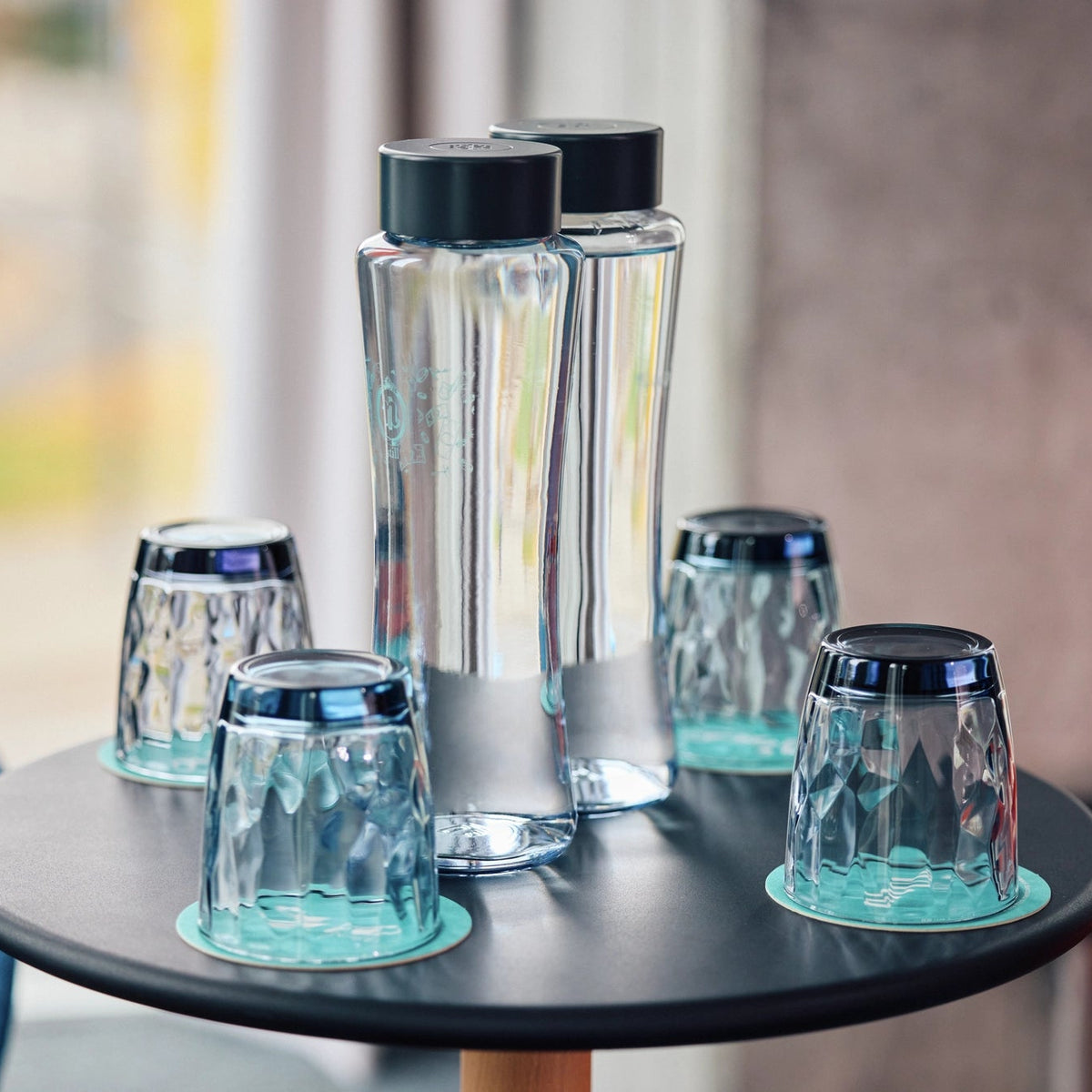 BRITA Twist bottles with black caps standing on a round black table.