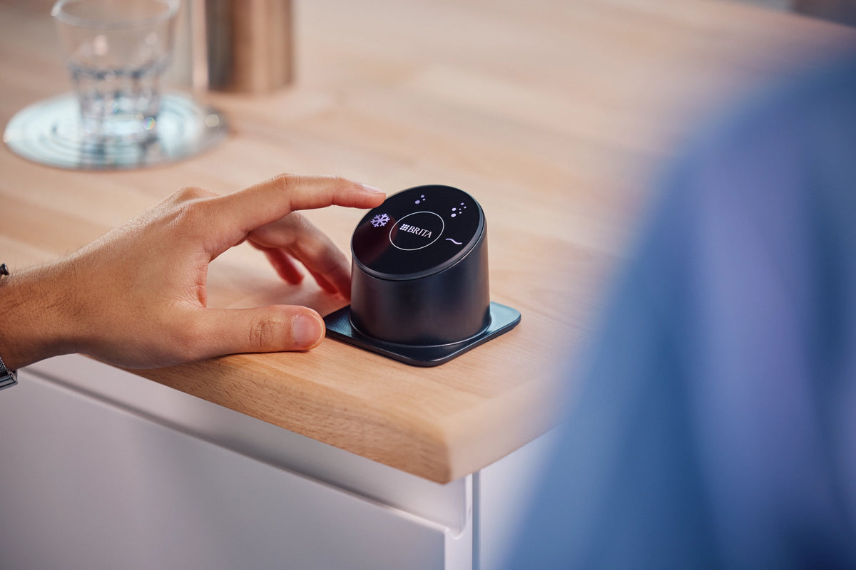 Person interacting with the BRITA Easy Access Panel to dispense water.